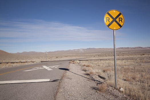 Railroad crossing tracks in the desert with blue skies.