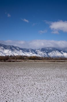 A high desert mountain range with snow on it.farm country