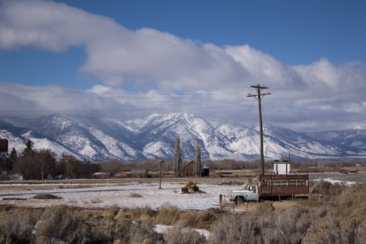 A high desert mountain range with snow on it.farm country