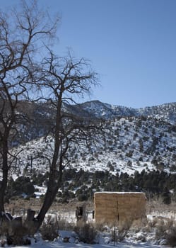 A high desert mountain range with snow on it.farm country