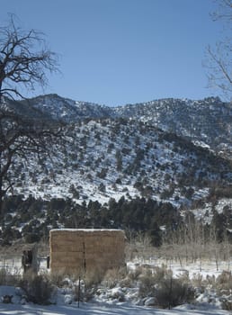 A high desert mountain range with snow on it.farm country