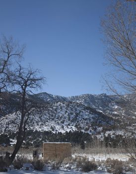 A high desert mountain range with snow on it.farm country