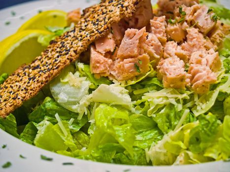 Grilled Salmon Caesar Salad Garnished with a Seeded Cracker