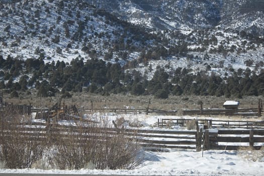 A high desert mountain range with snow on it.farm country