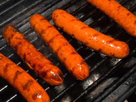 A row of five hotdogs on a bbq grill