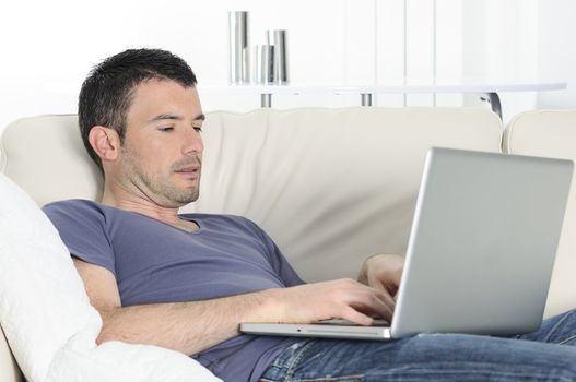 attractive relaxed man is working at home on a sofa