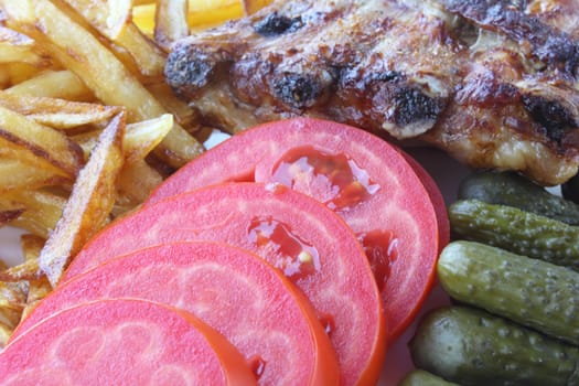 Grilled pork ribs with roasted potatoes, fresh tomato and pickle cucumbers