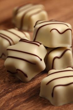 Photo of delicious white chocolates on wood table.