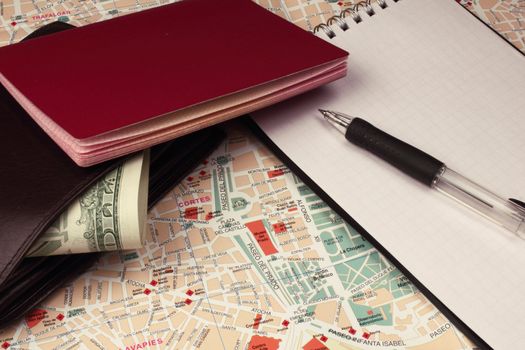 Wallet, passport,notebook and pen on city map.