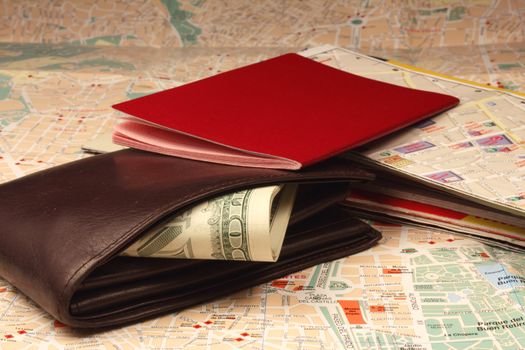 Wallet, passport and stack of maps on city map.