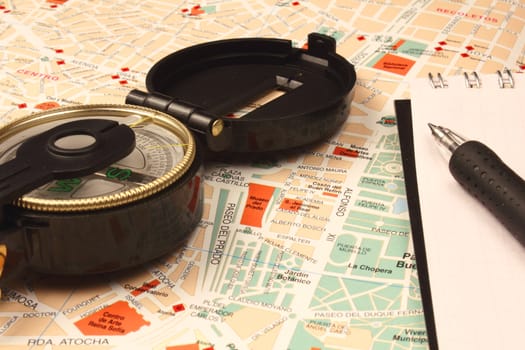 Compass, notebook and pen on city map.