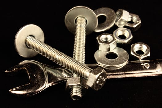 Wrench, bolts, nuts and washers on black background