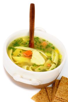 Chicken Noodle Soup with Parsley and Carrot in White Bowl with Wooden Spoon and Crispy Bread closeup on white background