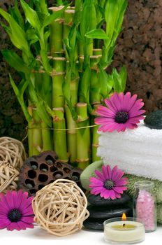 Spa scene with bamboo, towels, aromatic candles, bath salt, pebbles and daisies