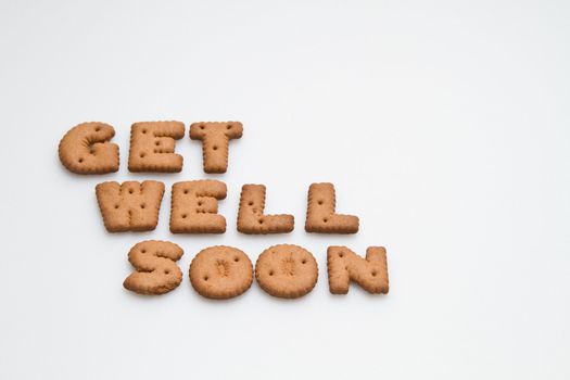 Get well soon wording made by brown biscuits on white surface landscape orientation