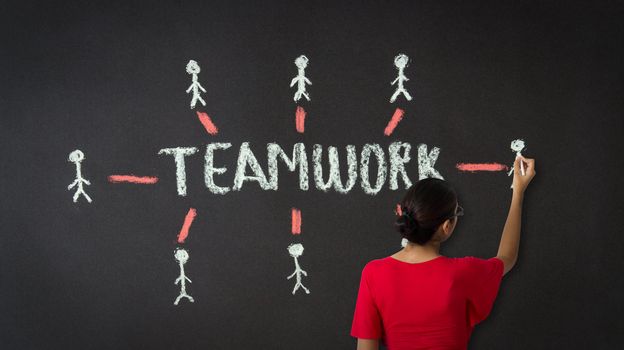 A person drawing a teamwork diagram with chalk on a blackboard.