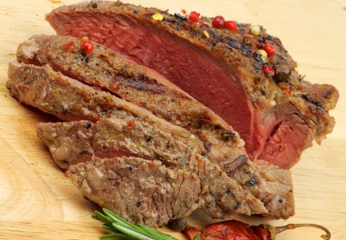 Slices of Ripe Roast Beef with Herbs and Spices closeup n Wood Cutting Board