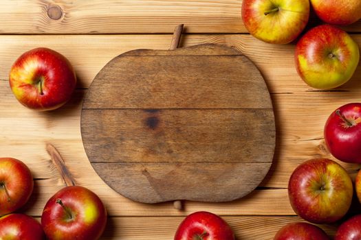 Fresh apples on wooden table. Composition with fruits and cutting board with apple shape. Copy space