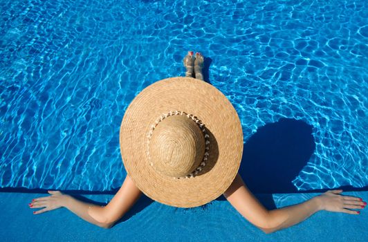 Woman in hat relaxing at the pool 