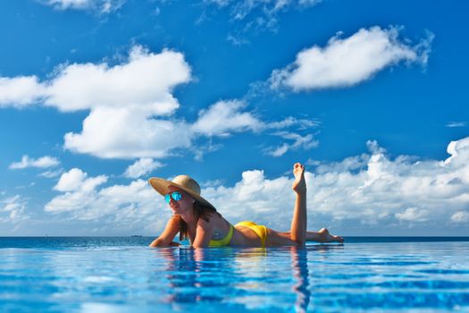 Woman in hat relaxing at the pool 