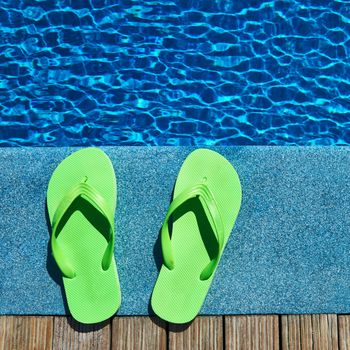 Green sandals by a swimming pool 