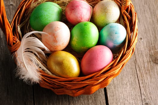 Colored easter eggs in basket on wooden table