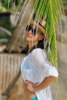 Woman in sunglasses near palm tree wearing hat