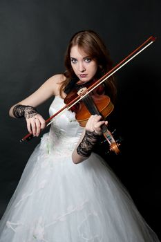 Girl in white dress with violin on black background
