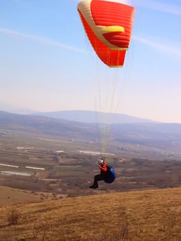 paraglider airborne over valley with hills in distance