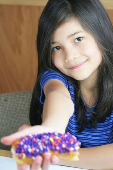 Girl holding colorful donut, ready to eat;