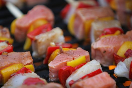 fresh fish on grilling sticks, salmon and halibut with red and yellow pepper being barbecued, very delicious looking
