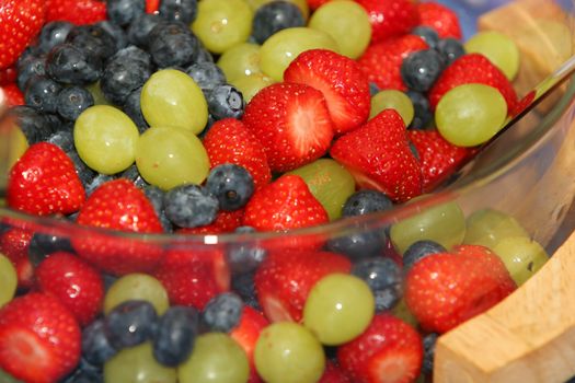 A dish of fresh berries, strawberries, blueberries, grapes 