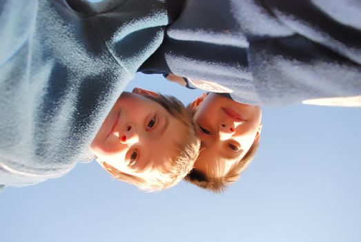 two boys play outside. They are looking down at us and we are on the ground