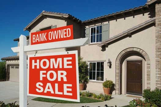 Bank Owned Home For Sale Sign in Front of New House on Deep Blue Sky