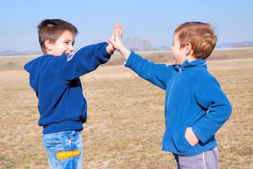 boys playing gimme five outside on a sunny day