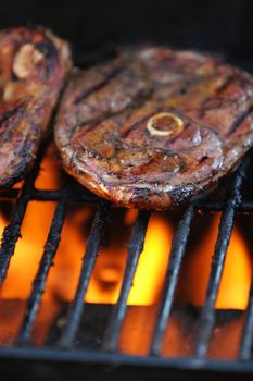 Lamb chops being barbecued on a gasgrill, flames visible beneath meat