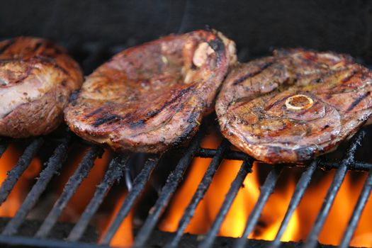 Lamb chops being barbecued on a gasgrill, flames visible beneath meat