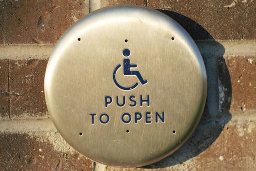 Handicap push to open button along exterior brick wall