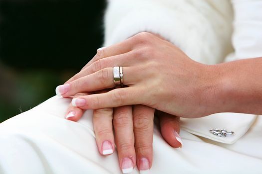 A wedding,bride sitting with hands in lap, cropped shot with focus on hands and wedding ring