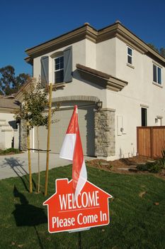 Welcome, Please Come In Real Estate Sign in Front of New Home