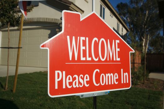 Welcome, Please Come In Real Estate Sign in Front of New Home