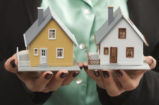 Female hands holding two houses.