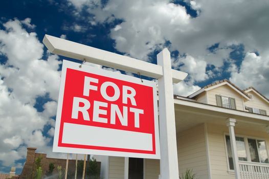 For Rent sign in front of new home with dramatic Blue Sky and clouds behind.