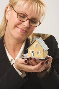 Female holding and looking at small house.