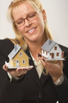 Female holding two houses contemplating each.