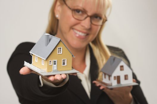 Female holding two houses and presenting one.