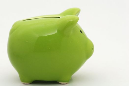 A green piggy bank isolated on white background, shot  from the side