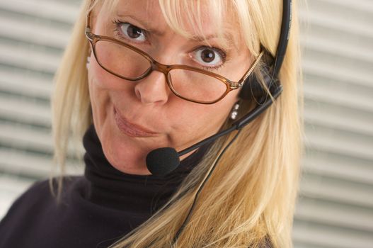 Goofy businesswoman talks on her phone headset.