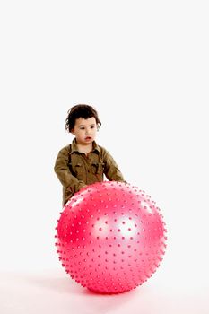 A little boy plays with a big pink ball