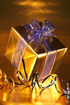 Elegant gold present with blue ribbons on  gold background.